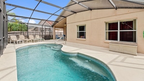 An indoor swimming pool with a glass ceiling, lounge chairs, and a view of palm trees. - Soaring Eagle at Eagle Point by Shine Villas 102 (Kissimmee)