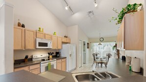 A modern kitchen with wooden cabinets, a microwave, stove, and a sink. - Soaring Eagle at Eagle Point by Shine Villas 102 (Kissimmee)