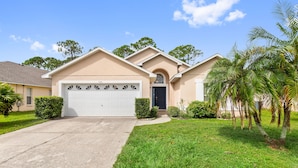 A residential house with a garage, a well-maintained lawn, and palm trees. - Soaring Eagle at Eagle Point by Shine Villas 102 (Kissimmee)