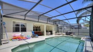An indoor swimming pool with a covered patio area, lounge chairs, and a barbecue grill. - Greenview Bliss by Shine Villas #031 (Davenport)