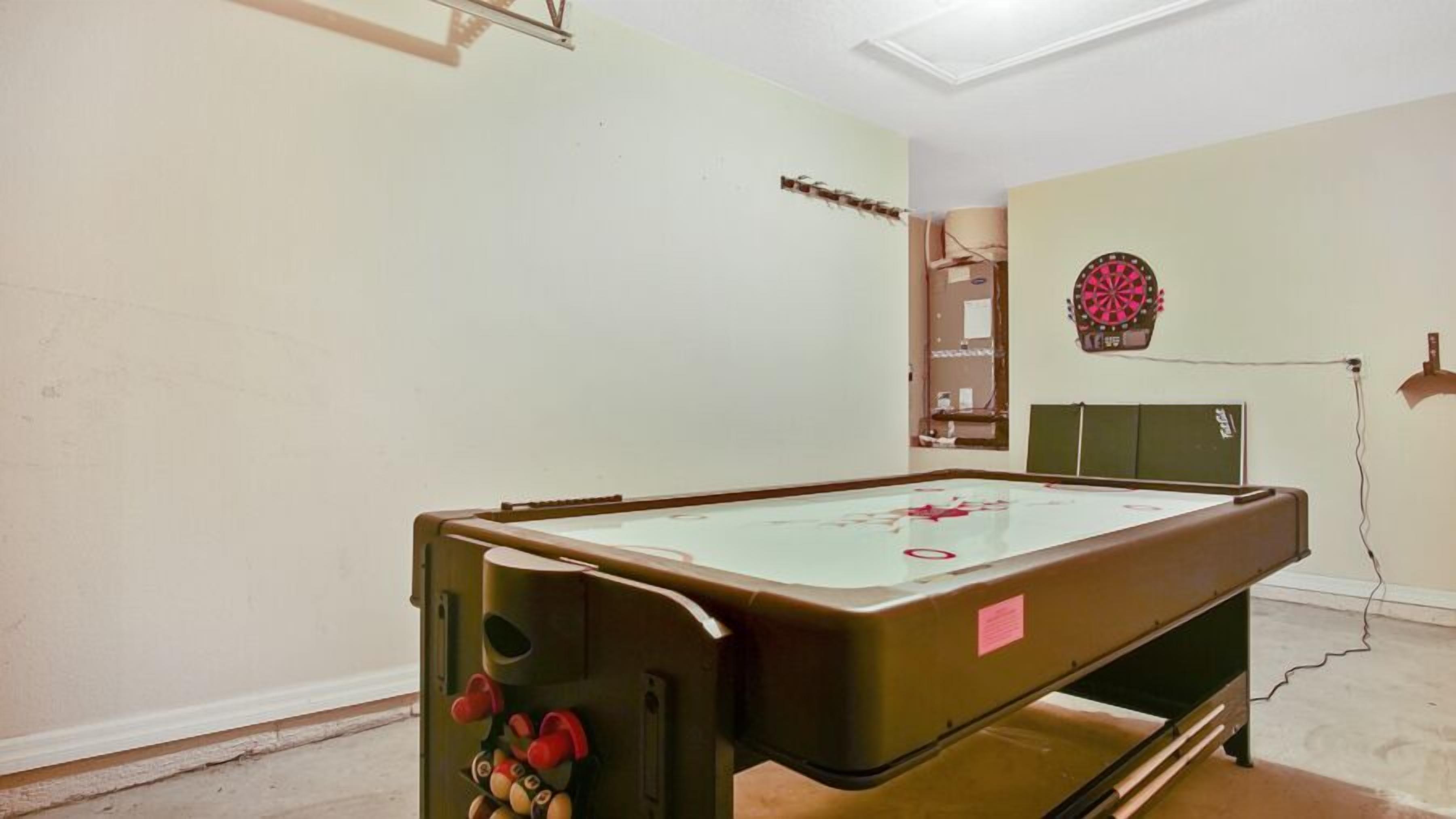 Una habitación con mesa de billar, dardos y un armario verde.