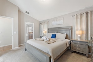 A bedroom with a large bed, a nightstand, a lamp, and a painting on the wall.