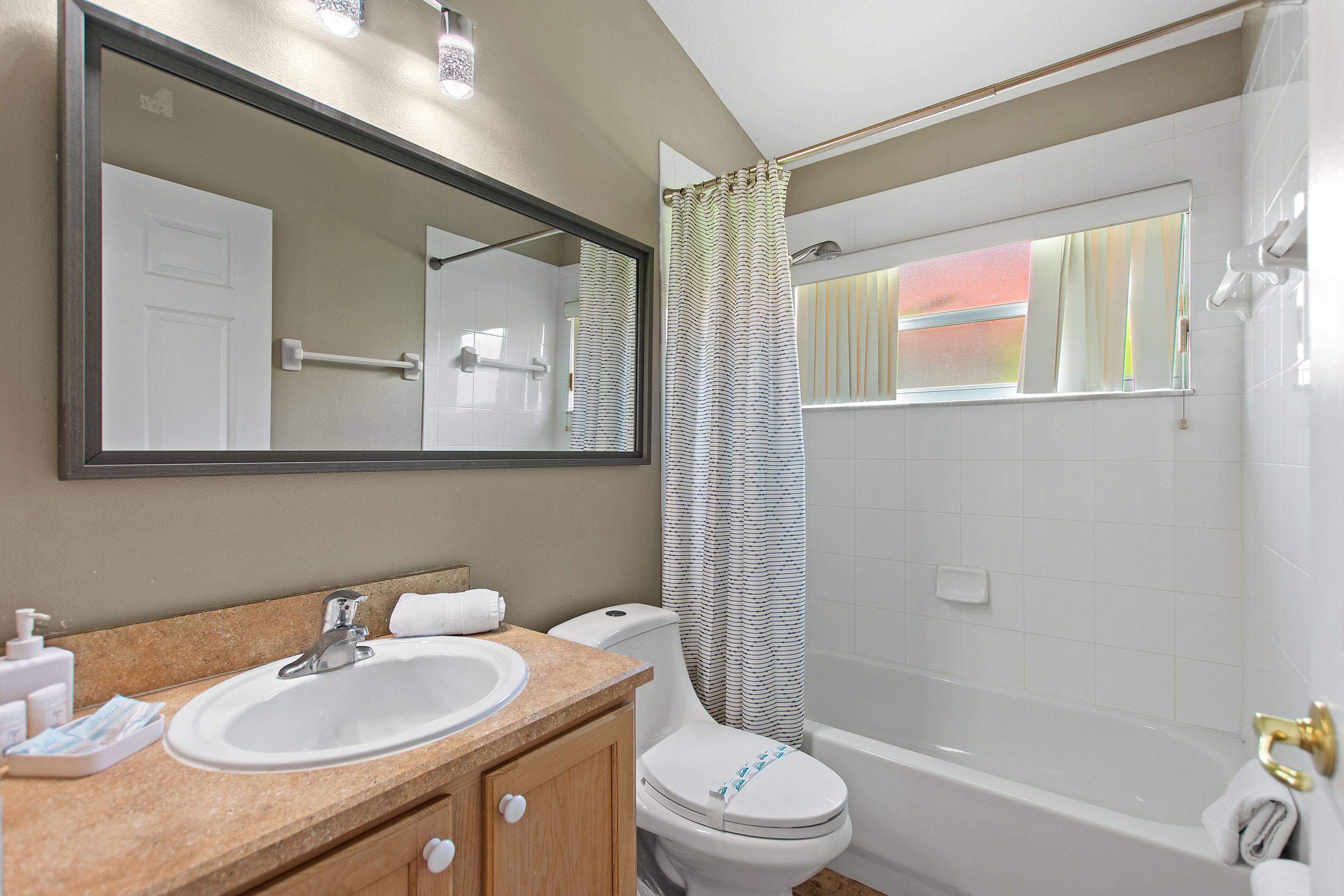 A bathroom with a sink, mirror, toilet, and bathtub.