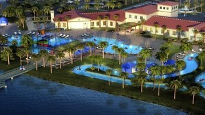 A resort with multiple swimming pools, palm trees, and a large building with a red roof. - Summer Solstice @ Windsor Westside by Shine Villas #114 (Kissimmee)