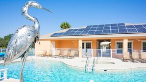Una piscina con techo de paneles solares, sillas de descanso y una estatua de pájaro.