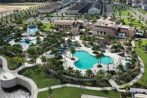 An aerial view of a resort with a central swimming pool, palm trees, and a water slide. - Camp Mickey - Resort Home, Spa, by Shine Villas 841 (Kissimmee)