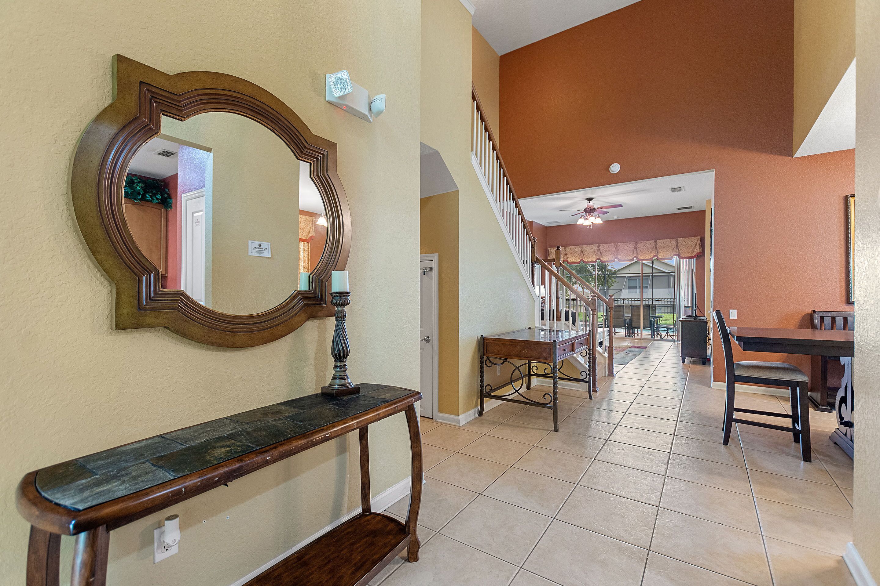 A spacious interior with a staircase, a dining area, and a large mirror.