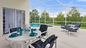 Une terrasse extérieure dotée d’un espace salon couvert, d’une piscine et offrant une vue sur le paysage environnant.