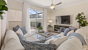 Ein modernes Wohnzimmer mit einer Sofagarnitur, einem Couchtisch, einem Fernseher und einem Deckenventilator.