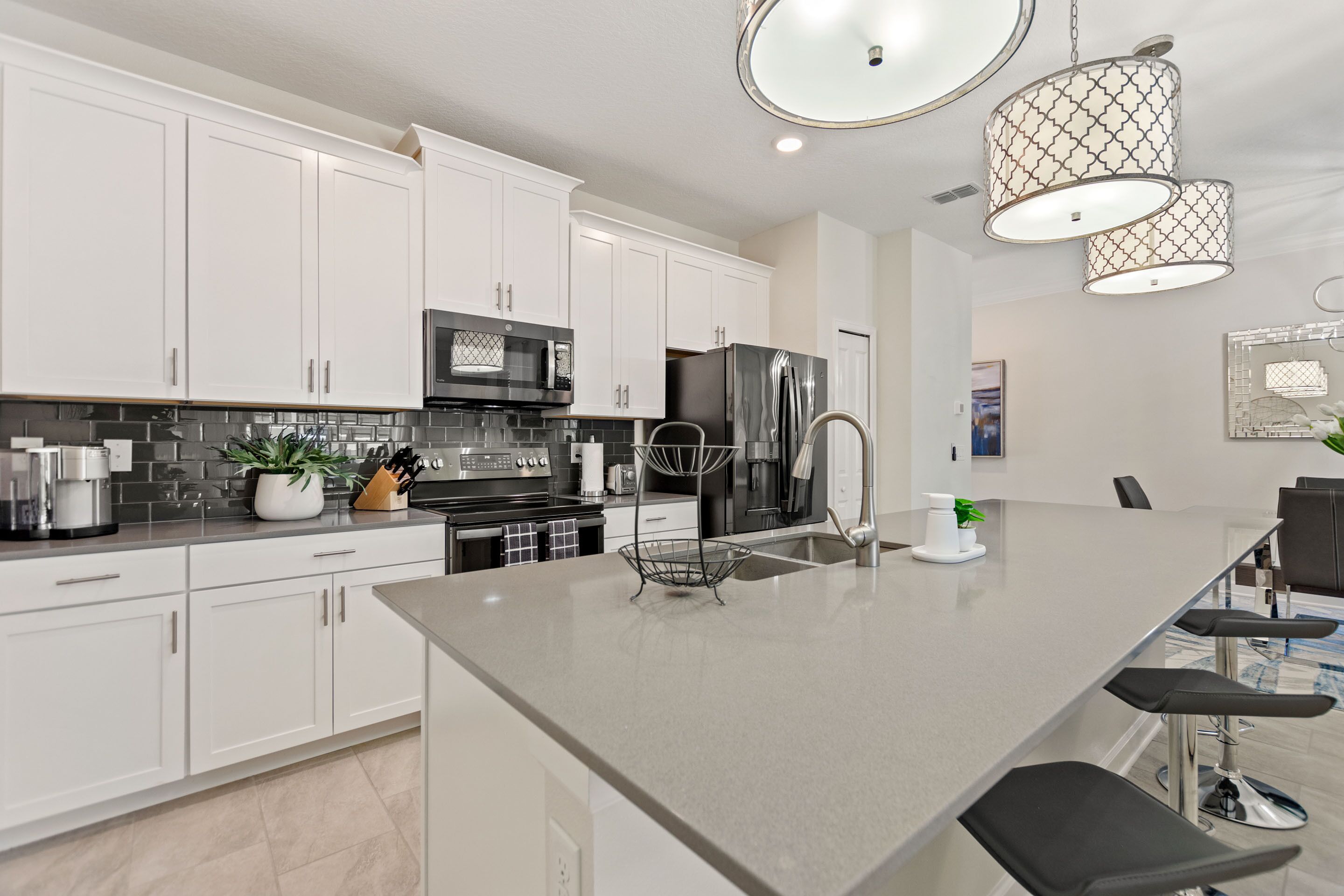 A modern kitchen with white cabinets, stainless steel appliances, and a large island with bar stools.