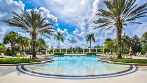 A swimming pool surrounded by palm trees and lounge chairs, with a clear blue sky above. - Wildviews by Shine Villas at Watersong Resort! #024 (Davenport)