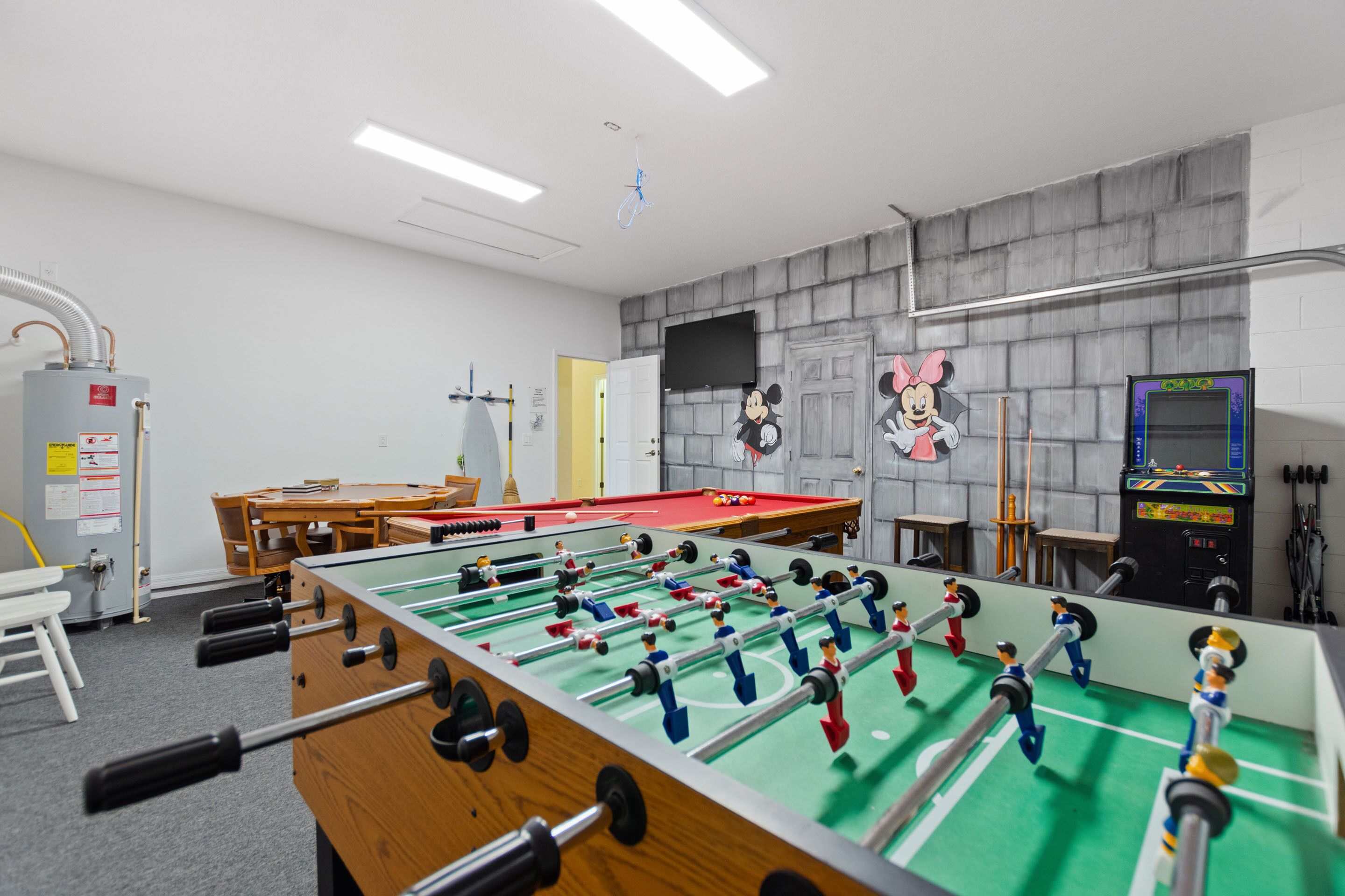 Una habitación con mesa de fútbol, mesa de billar y televisión montada en la pared.