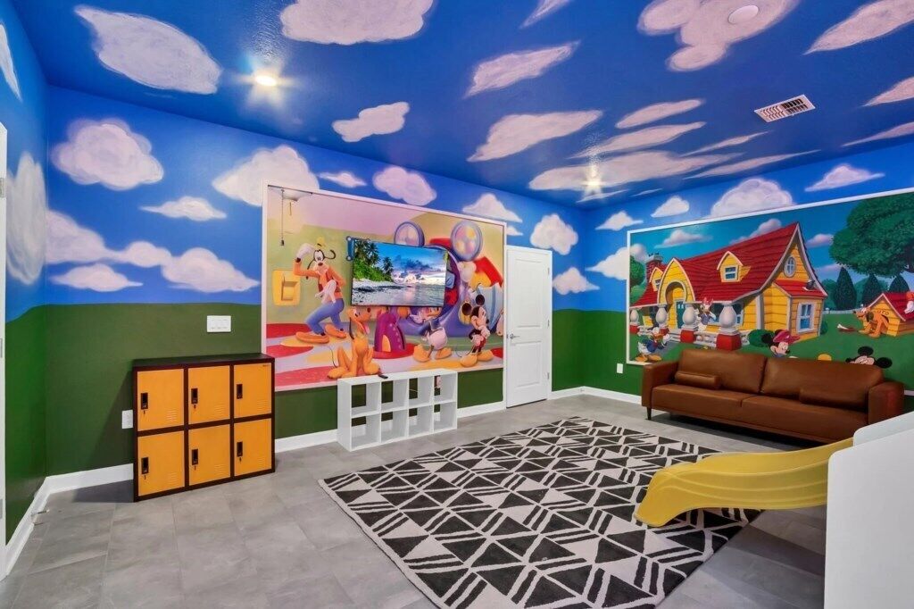 A room with a blue ceiling, cloud murals, a couch, a yellow slide, and a geometric rug.