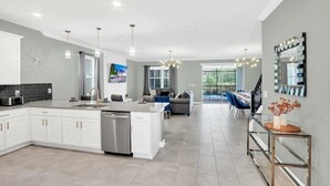 A modern kitchen with white cabinets, a central island, and pendant lighting. - Jurassic Water View @storey Lake by Shine Villas! Sleeps up to 24! #021 (Kissimmee)