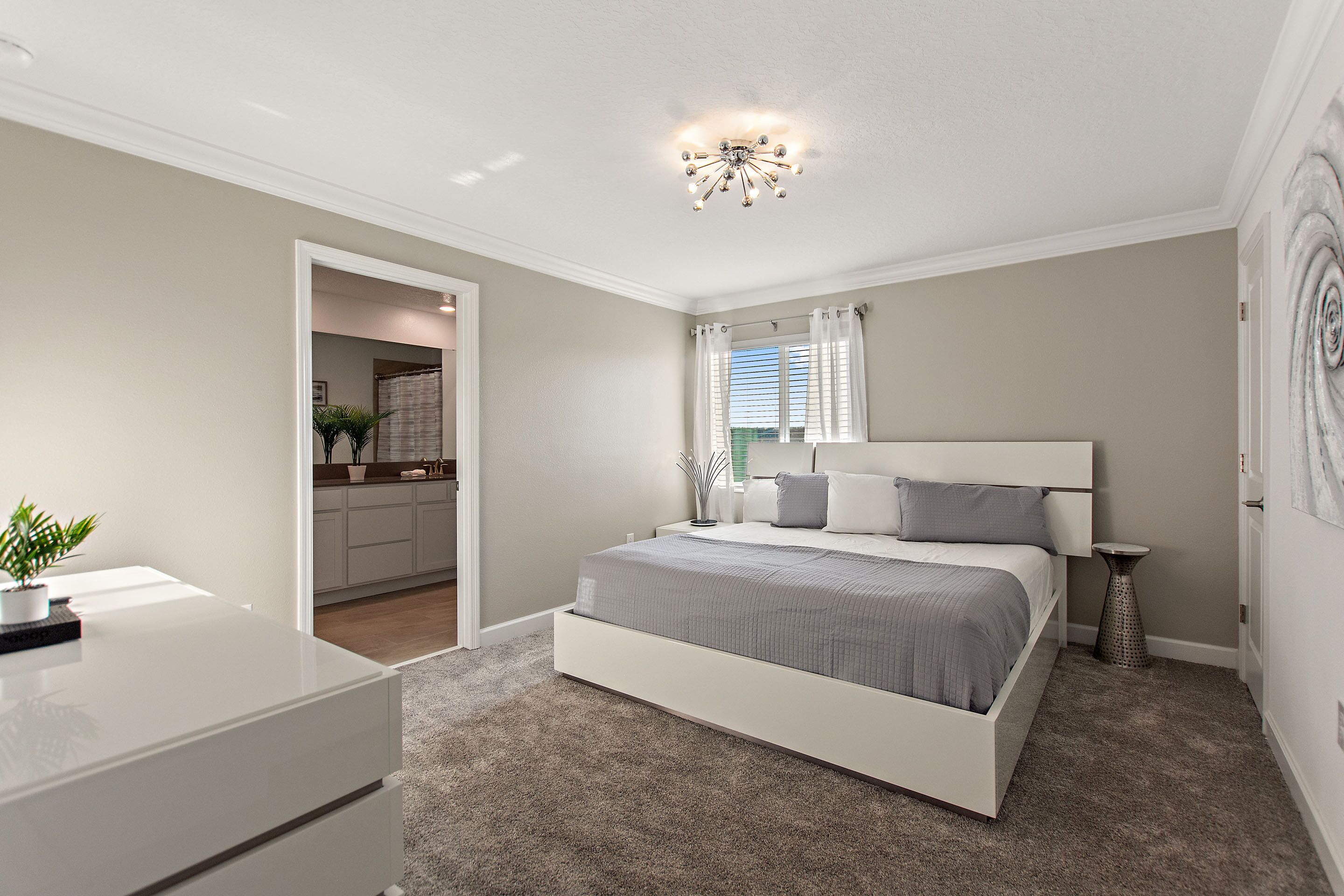 A bedroom with a bed, bedside table, and a small potted plant.