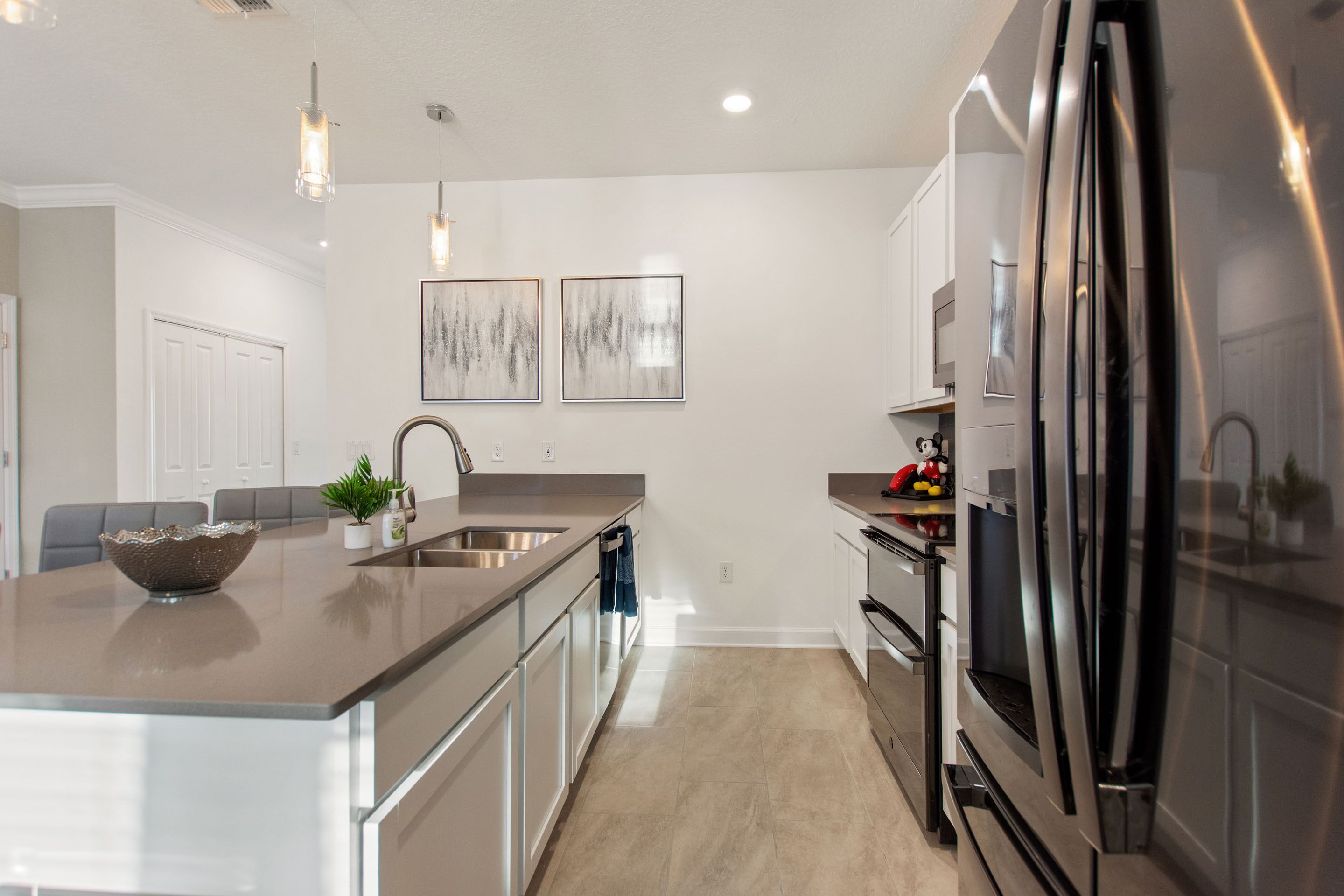 A modern kitchen with a large island, stainless steel appliances, and pendant lighting.