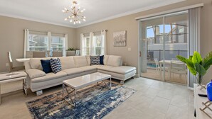 A modern living room with a sectional sofa, a coffee table, and a large window with curtains.