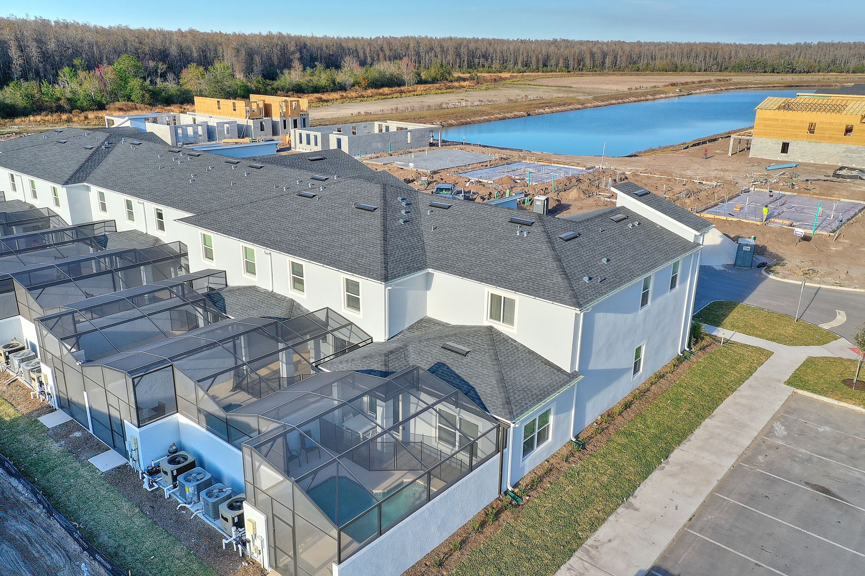 A residential complex with multiple houses, a swimming pool, and a large body of water in the background.