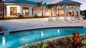 A resort with a swimming pool, lounge chairs, and a covered patio area.