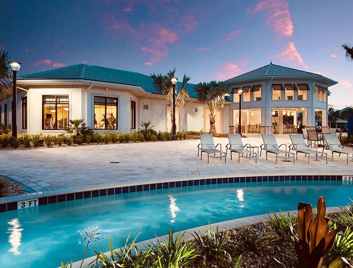 A resort with a swimming pool, lounge chairs, and a covered patio area.