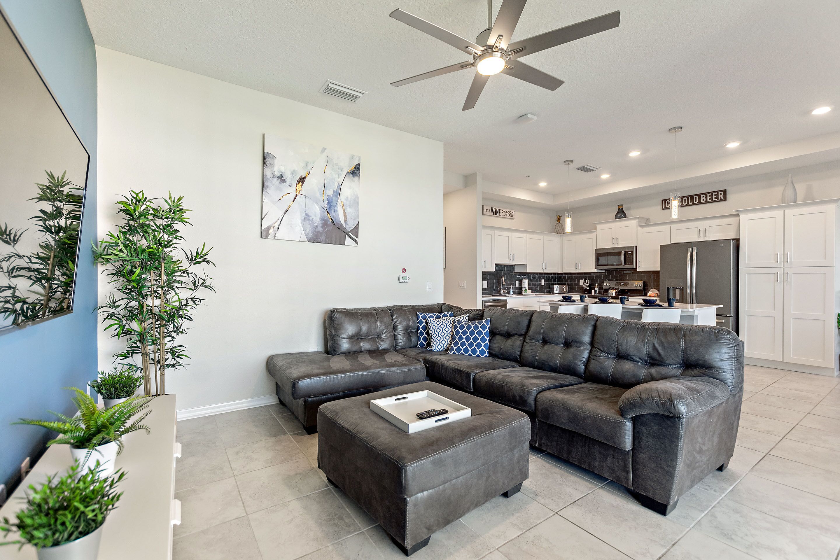 A modern living room with a sectional sofa, a coffee table, and a ceiling fan.