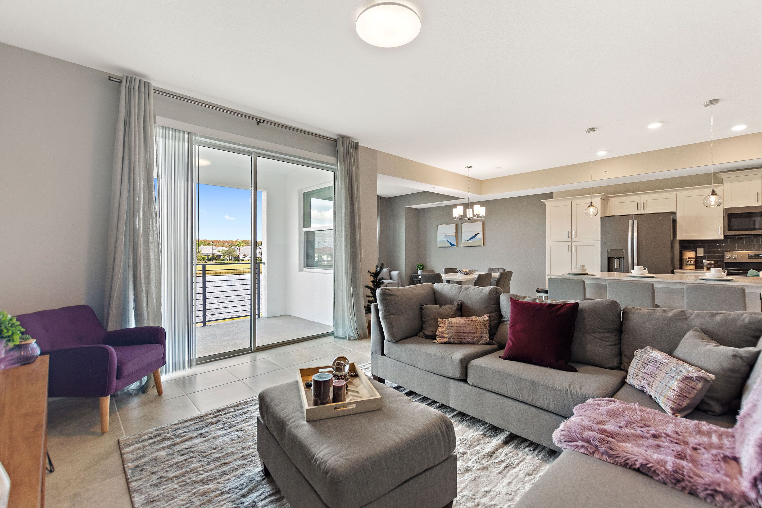 A modern living room with a grey sofa, a purple armchair, and a wooden coffee table.