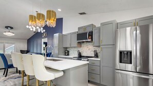 A modern kitchen with grey cabinets, stainless steel appliances, and a central island with bar stools. - Breathe Easy at Solterra Resort by Shine Villas 706 (Davenport)