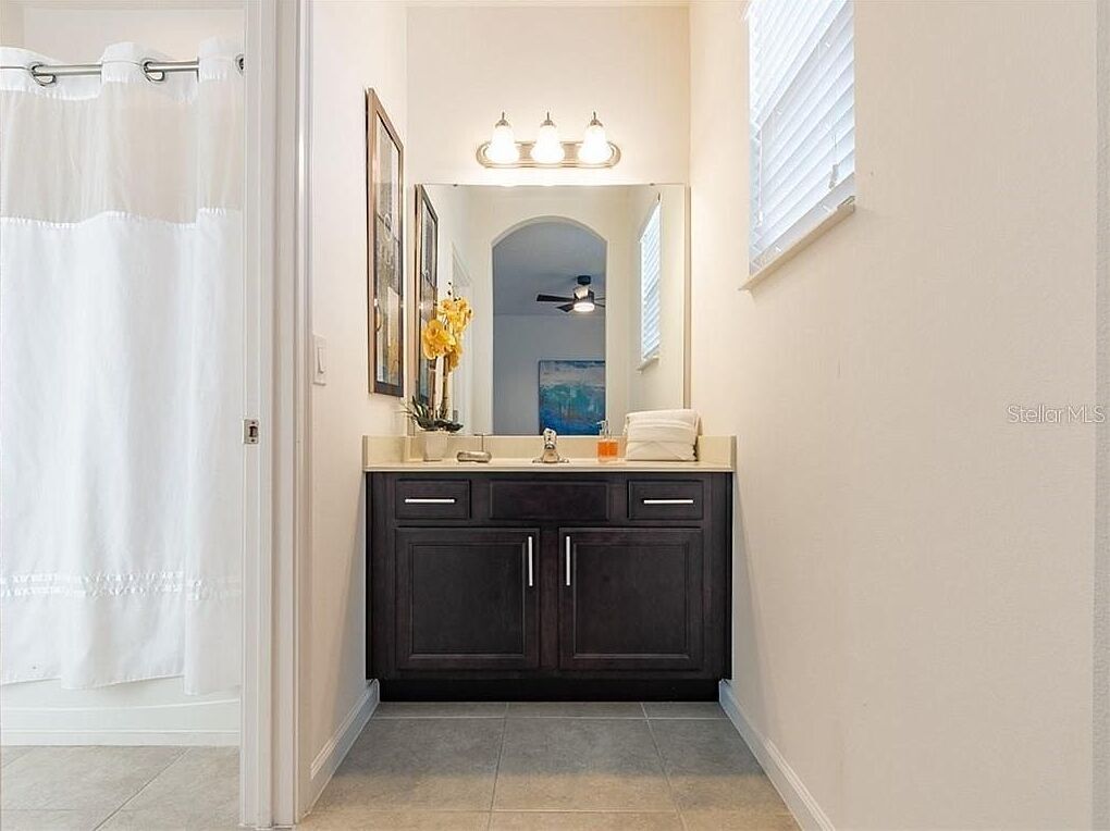 A bathroom with a dark vanity, a mirror, and a light fixture above the sink.