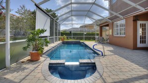 A covered swimming pool with a glass ceiling, surrounded by a brick patio and a house in the background. - 6 Bedroom Premium Home With Pool, Spa and Games Room #800 (Davenport)