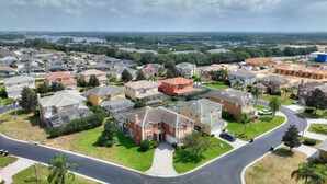 A residential area with houses, roads, and a body of water in the distance. - 6 Bedroom Premium Home With Pool, Spa and Games Room #800 (Davenport)
