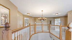 A grand staircase with a chandelier, white railings, and a framed picture on the wall. - 6 Bedroom Premium Home With Pool, Spa and Games Room #800 (Davenport)