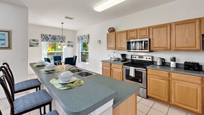 A modern kitchen with wooden cabinets, a stainless steel refrigerator, and a built-in oven.