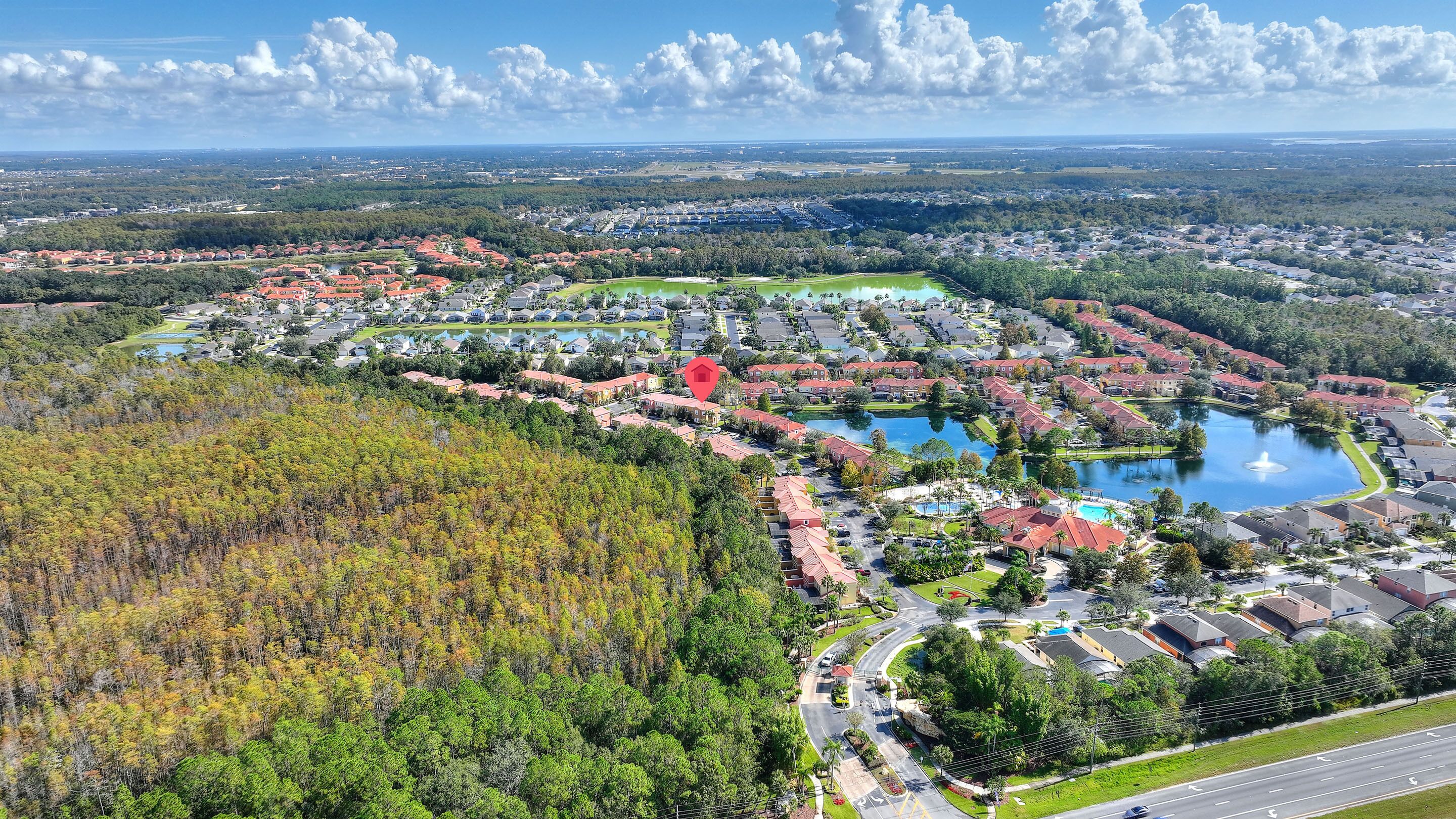 An aerial view of a residential area with houses, a central park, and a lake.