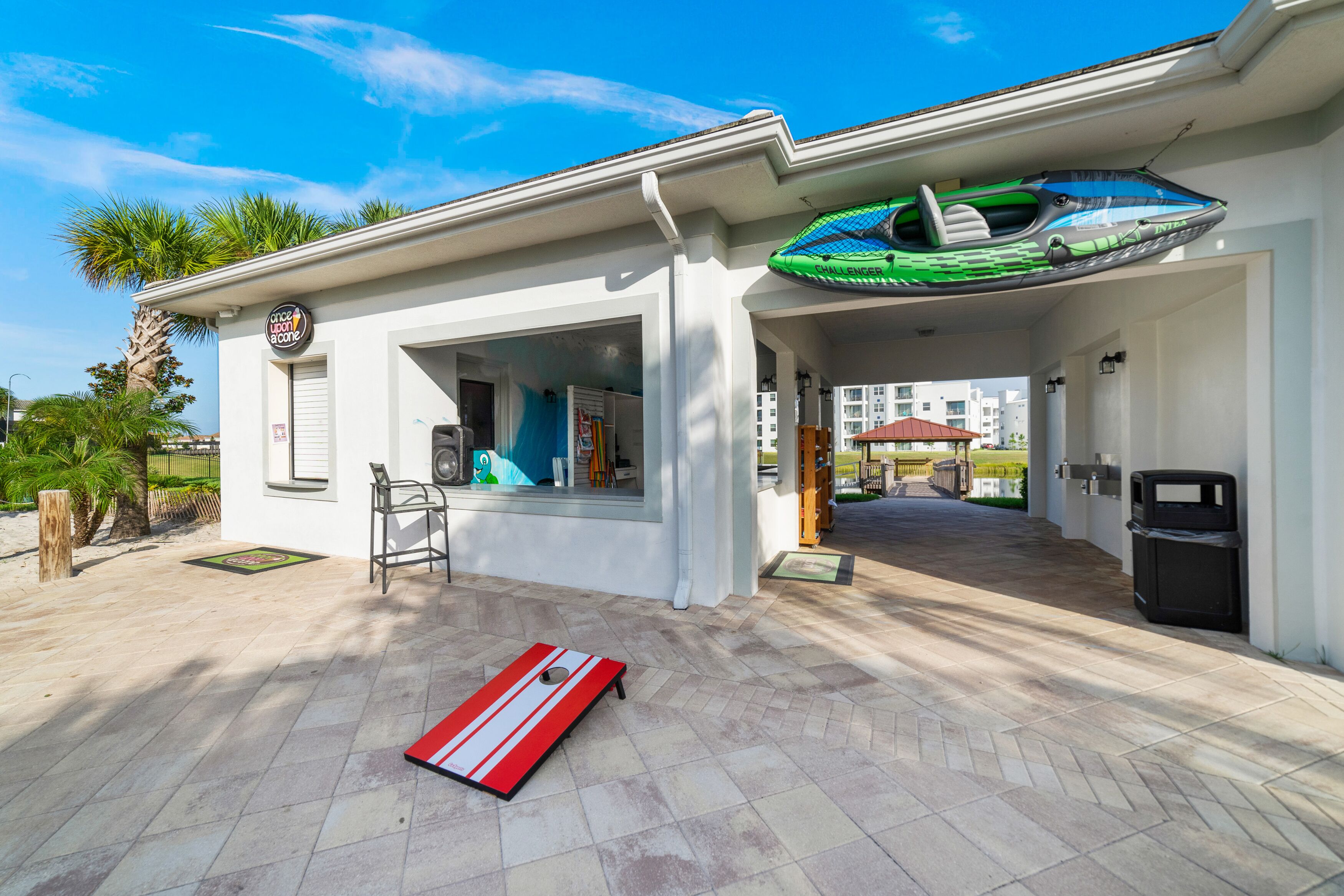 A modern building with a covered patio area, a small outdoor seating area, and a visible trash bin.