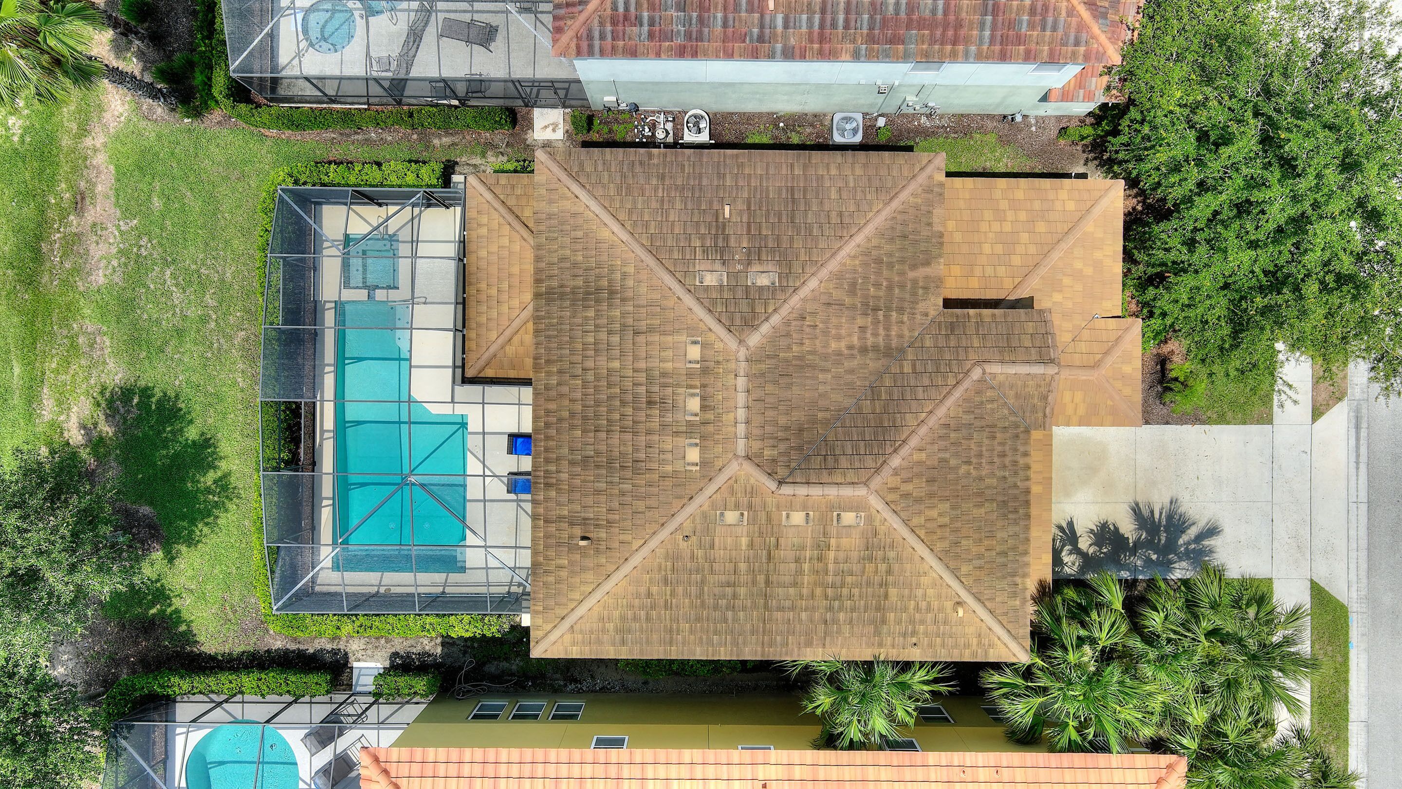 An aerial view of a building with a central courtyard, a swimming pool, and surrounding greenery.