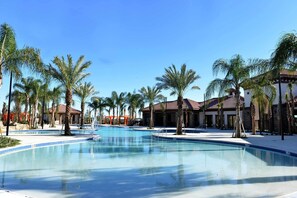 A large swimming pool surrounded by palm trees and buildings with red-tiled roofs. - Starstruck at Solterra Resort by Shine Villas #101 (Davenport)
