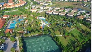 An aerial view of a residential area with a swimming pool, tennis courts, and houses. - Brilliance at Solterra Resort by Shine Villas #092 (Davenport)