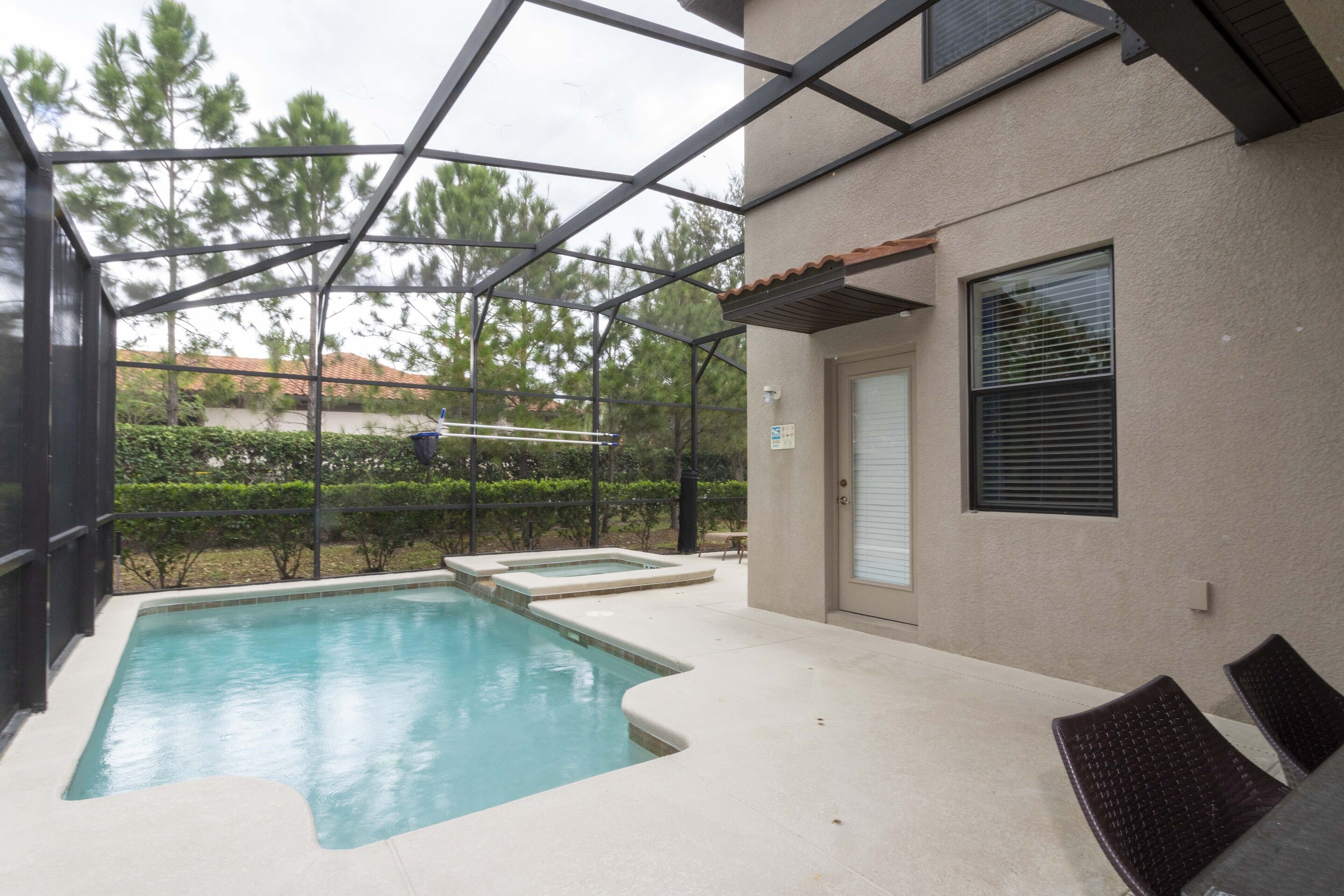 A swimming pool with a glass enclosure, a door, and a window with blinds.