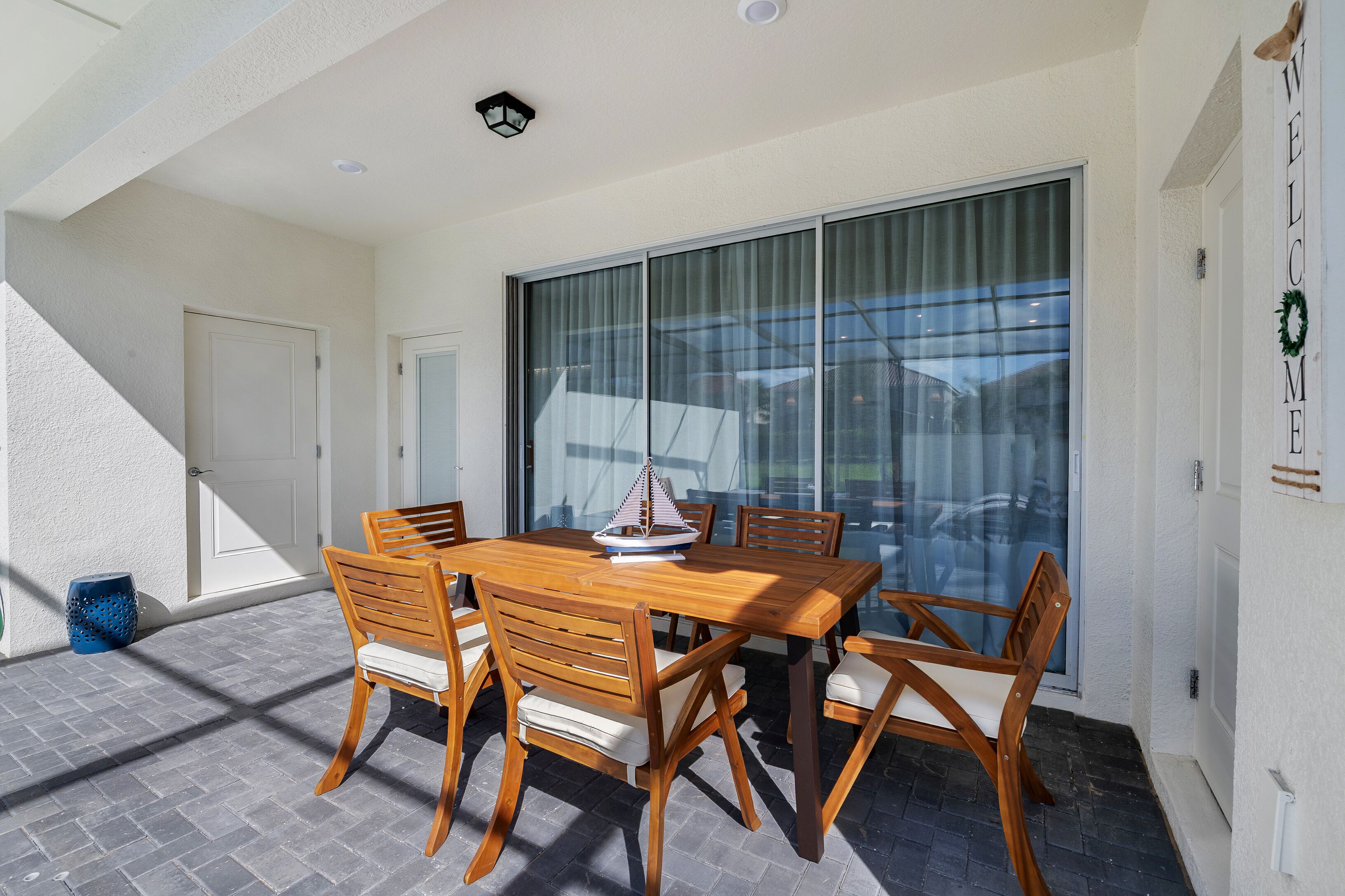 A patio with a wooden table and chairs, a ship model, and a large sliding glass door.