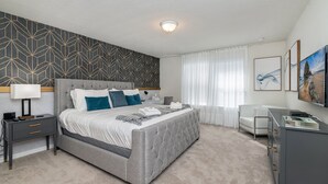 Quarto moderno com uma cama grande, mesas de cabeceira, uma escrivaninha e uma cadeira.