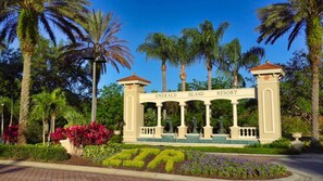 A resort entrance with a sign reading "Emerald Island Resort" surrounded by palm trees and landscaped gardens. - Emerald Island Resort, Private Pool, Games Rm #823 (Kissimmee)
