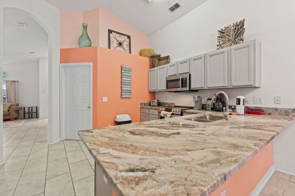 A kitchen with white cabinets, a granite countertop, and a microwave.