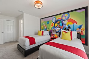 A hotel room with two beds, a colorful mural on the wall, and a white door. - Sea Shore at Solara Resort 401 (Kissimmee)