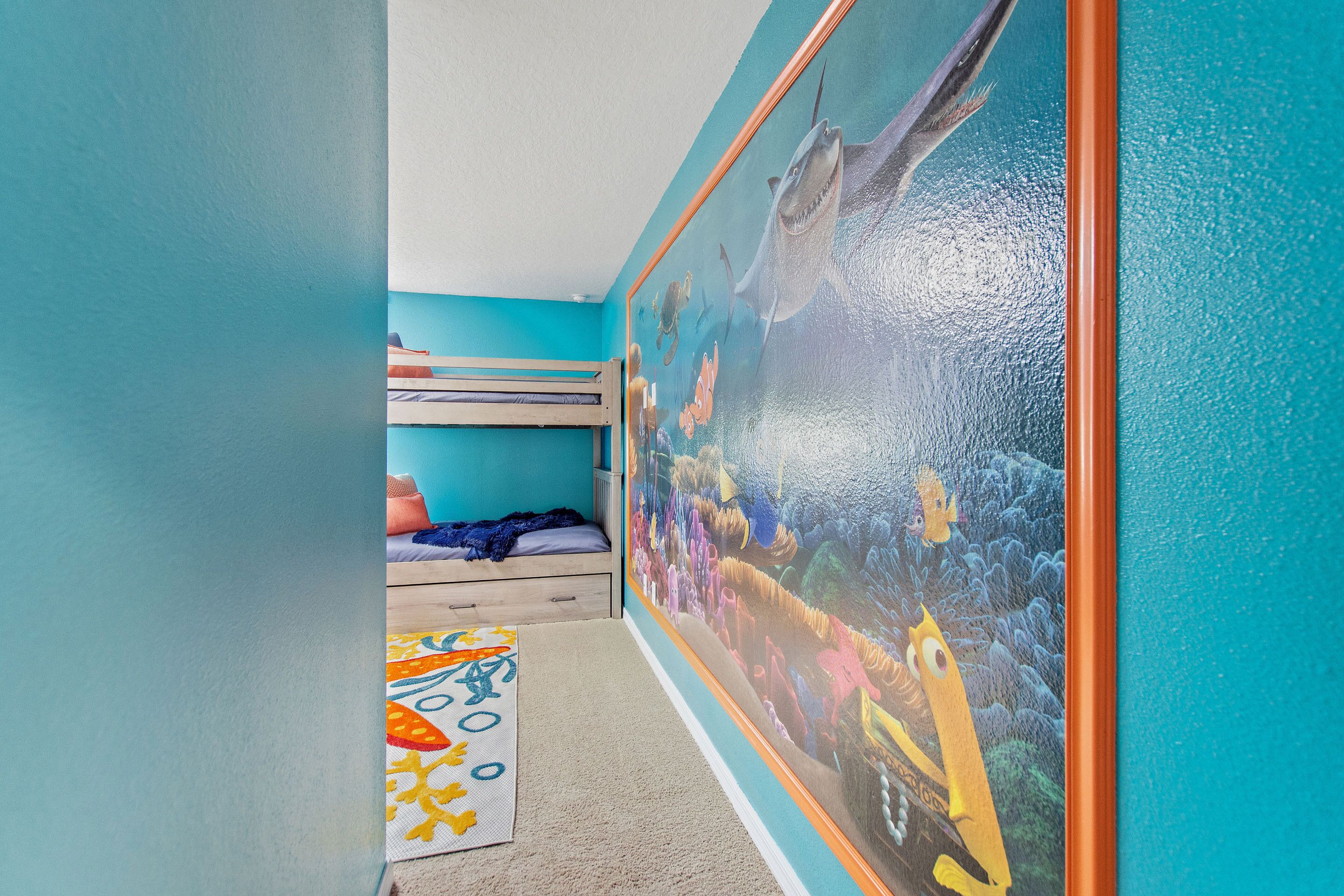 A child's bedroom with a mural of sea creatures, a bunk bed, and a colorful rug.