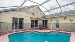 Une piscine dotée d’un toit en verre, d’une porte et de deux chaises.