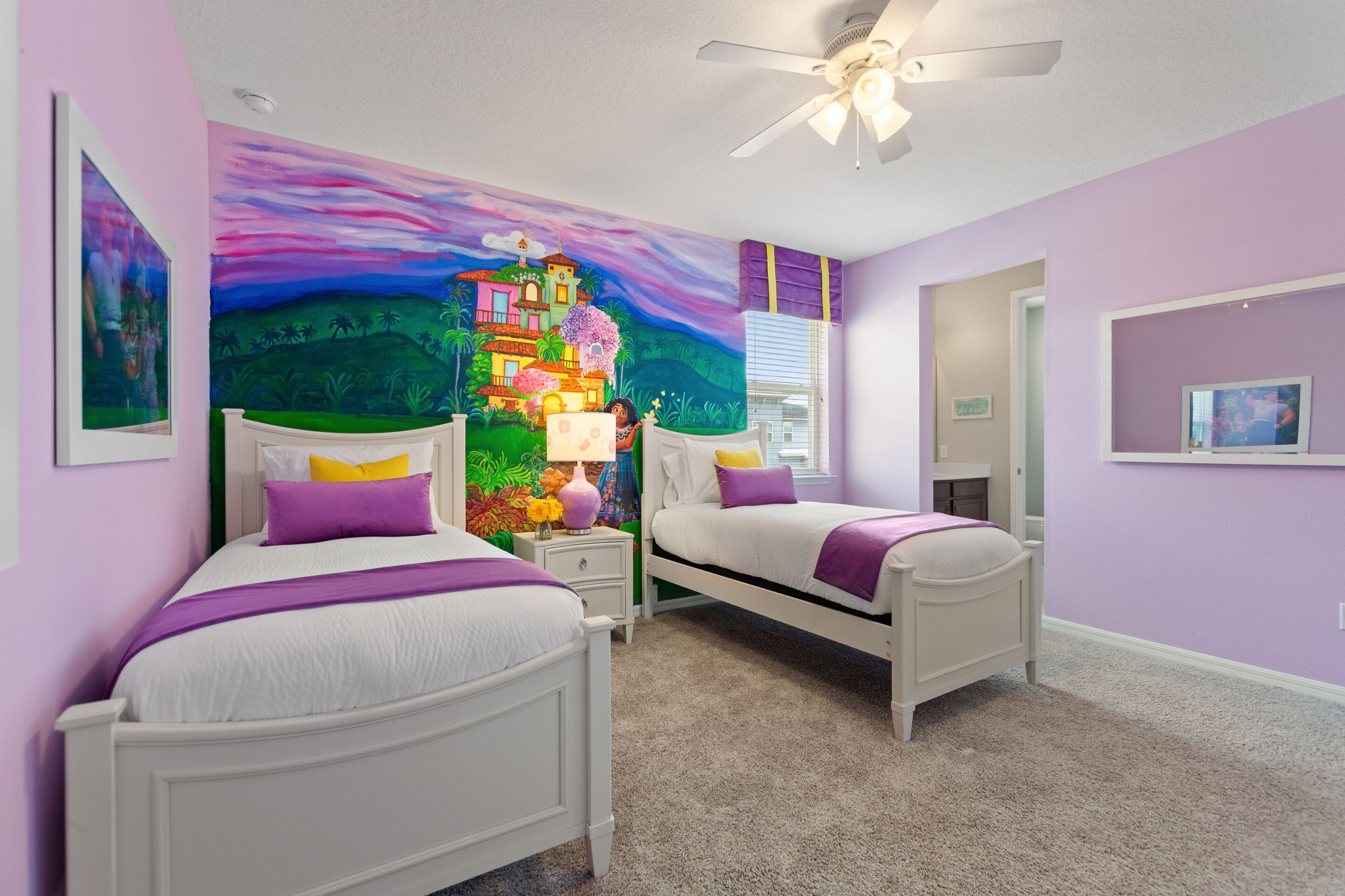 Quarto com duas camas, ventilador de teto e um mural colorido na parede.