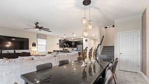Ein modernes Wohnzimmer mit Esstisch, Sofas und einer Küche im Hintergrund.