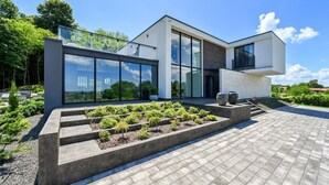 A modern two-story house with large glass windows, a flat roof, and a landscaped garden with steps leading to the entrance. - Stunning home in Vinogradi Ludbreski with sauna (Vinogradi Ludbreski)