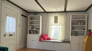 A room with a built-in bench seat, white cabinets, and a window with sheer curtains. - Cozy two bedroom house in the heart of Gloucester (Gloucester)