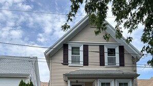 A two-story house with a front porch, a small staircase leading to the entrance, and a mailbox. - Cozy two bedroom house in the heart of Gloucester (Gloucester)